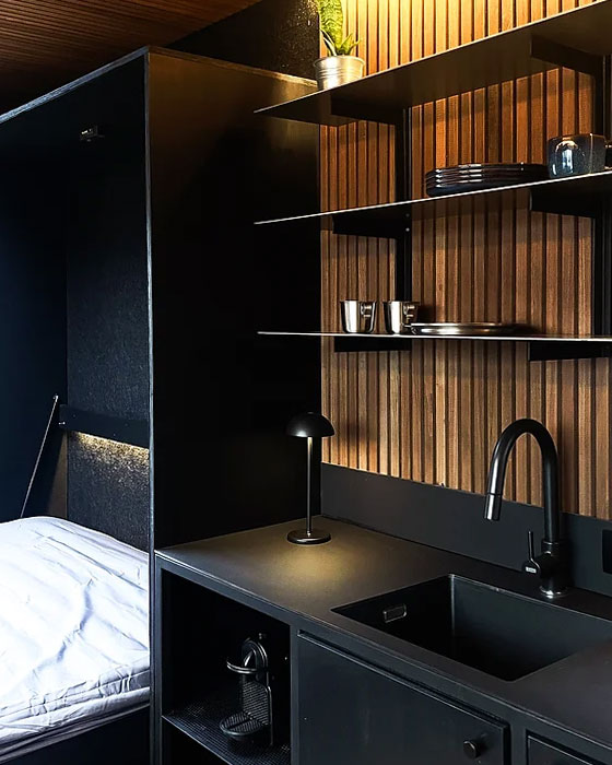 cuisine sur mesure en bois noir et lit dans un petit espace